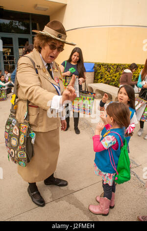 Une femme en uniforme historique fidèlement Girl Scouts fondateur "Miss Daisy" Juliette Gordon Droit et démontre l'éclaireuse promettent d'une marguerite du scoutisme à un témoin saison de vente atelier à Irvine, CA. Remarque sac d'épaule avec des correctifs. Banque D'Images