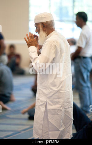 Un vieil homme du Moyen-Orient dans la tradition musulmane robe prie pendant l'après-midi services à un Anaheim, CA, mosquée. Banque D'Images
