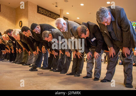 Les hommes adultes arc dans la prière pendant les services religieux dans une mosquée à Mission Viejo, CA. Remarque L'arabe écrit sur le mur. Banque D'Images
