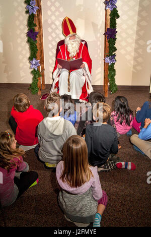 Un acteur en Saint Nicolas et portant une mitre se lit à haute voix aux enfants des histoires de Noël pendant l'avent activités à un Laguna Niguel, CA, l'église catholique. L'Avent est un temps observé dans plusieurs églises chrétiennes occidentales, à la fois des femmes enceintes l'attente et la préparation de la célébration de la nativité de Jésus à Noël. Banque D'Images