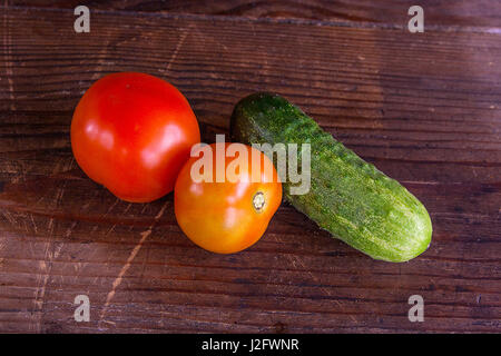 Tout fraîchement cueillis mûrs rouges tomates et concombres sur le fond en bois Banque D'Images