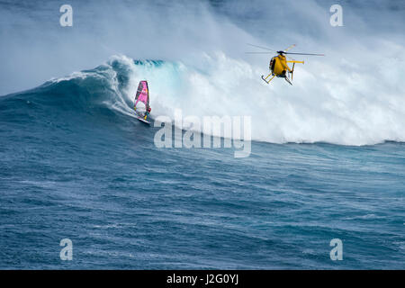 USA, Hawaii, Maui. L'homme à la caméra de filmer l'hélicoptère Robby Naish champion du monde de planche à voile de vagues de monstre à Pe'ahi Jaws, Rive Nord de Maui. Banque D'Images