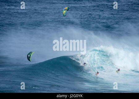 USA, Hawaii, Maui. Robby Naish et Niccolo Porcella le kitesurf avec un autre surfeur sur une vague de monstre à Pe'ahi Jaws, Rive Nord de Maui. Banque D'Images