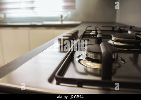 Cuisine équipée d'une cuisinière vitrocéramique avec la lumière en streaming à partir d'une fenêtre et d'un évier de cuisine dans l'arrière-plan. Banque D'Images