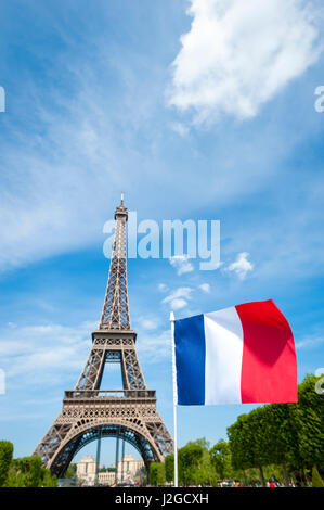 Drapeau français volant dans ciel bleu en face de la Tour Eiffel à Paris, France sur une journée de printemps Banque D'Images