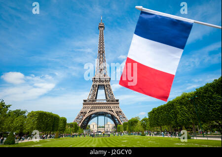 Drapeau français volant dans ciel bleu en face de la Tour Eiffel à Paris, France sur une journée de printemps Banque D'Images