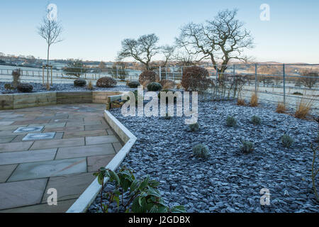 Vue d'hiver givré de jardin privé, avec l'élégant et contemporain, l'aménagement paysager et des plantations nouvelles dur sur billons - Yorkshire, Angleterre, Royaume-Uni. Banque D'Images