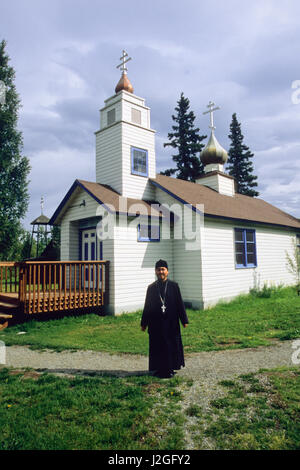 Homme d'Alaska vêtus de robes noires de la paroisse se trouve en face de l'Église orthodoxe russe Saint-nicolas à Eklutna Historical Park, situé à l'intérieur d'origine de l'Athabaskan, indiens. Eklutna Alaska Banque D'Images