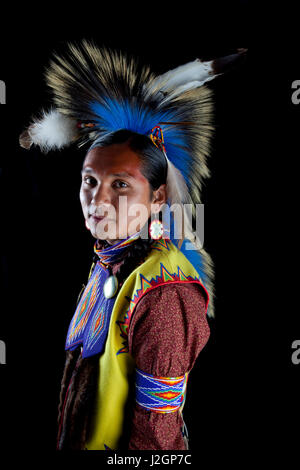 Teenage boy traditionnel habillé de pow wow regalia de perles et une coiffure roach en face de toile noire. Ian Stevens Banque D'Images