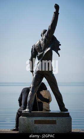 Un couple est assis au pied de la statue de Freddie Mercury, fin chanteur du groupe de rock britannique Queen, au bord du lac du lac Léman à Montreux, Banque D'Images