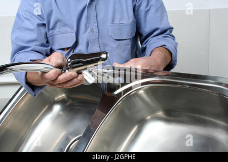 Plombier installation d'un robinet dans un évier de cuisine en acier inoxydable Banque D'Images