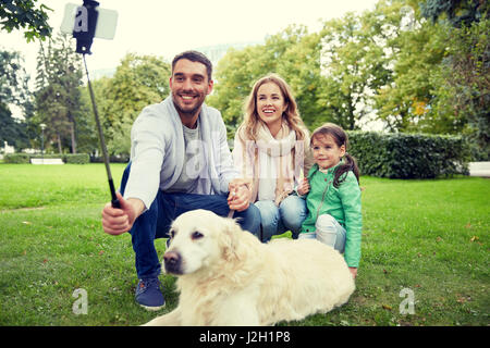 Famille heureuse avec chien en tenant le smartphone par selfies Banque D'Images