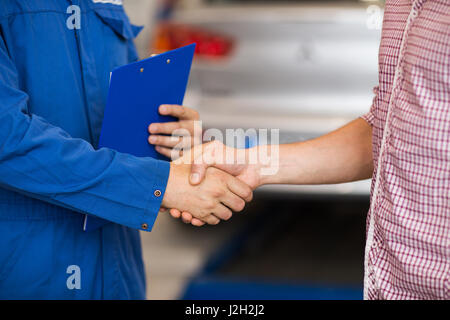 Mécanicien auto et man shaking hands at car shop Banque D'Images