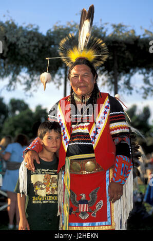 L'homme en costume traditionnel des Blackfeet jeunes mentors sur Blackfeet Reservation met bras autour de jeune garçon lors d'un rassemblement des Indiens d'Amérique (Montana) Banque D'Images