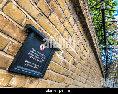 Panneau d'avertissement et les obstacles le long mur d'enceinte du palais de Buckingham, London, UK. Banque D'Images