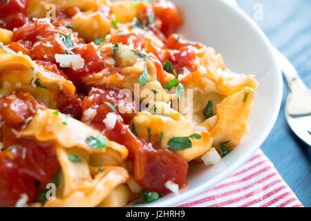 Tortellini frais fait maison avec de la sauce tomate, les herbes hachées et le fromage parmesan Banque D'Images