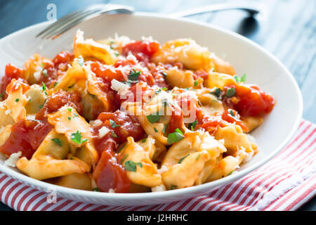 Tortellini frais fait maison avec de la sauce tomate, les herbes hachées et le fromage parmesan Banque D'Images