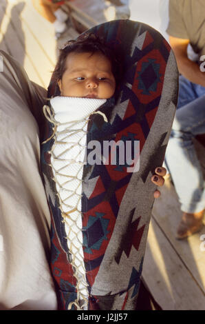 Native American baby avec lacets à l'intérieur d'un porte-bébé traditionnel recouvert d'une couverture Pendleton est tenu à son bras. (MR) Banque D'Images