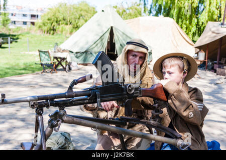 Salute to the 40s re-enactment. Enfant, garçon blond, 6-7 ans, en uniforme de l'armée britannique, étant montré comment fire la mitrailleuse Bren par Desert Rat soldat. Banque D'Images