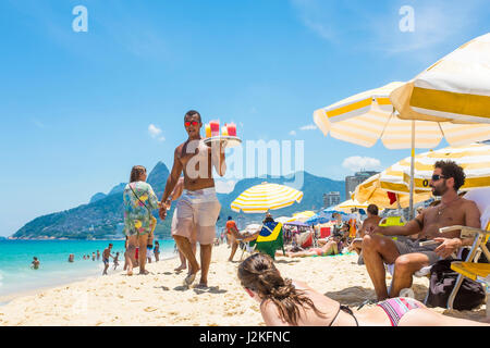 RIO DE JANEIRO - le 24 janvier 2017 : jeune Brésilien vendeur porte un plateau de caipirinha cocktails dans le soleil de midi sur la plage d'Ipanema. Banque D'Images