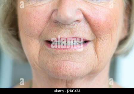 Face inférieure d'un senior femme avec Peau parcheminé avec ses lèvres légèrement entrouverte montrant le bout de ses dents dans une vue en gros plan Banque D'Images