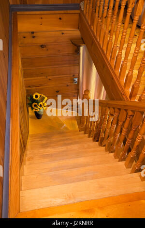 Escalier en bois de pin et d'érable menant au rez-de-chaussée à l'intérieur d'une maison en rondins de style cottage. Banque D'Images