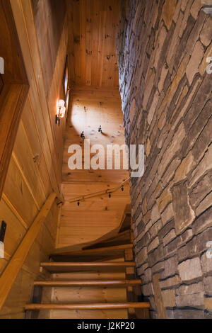 Escalier en bois flanquée de planche horizontale et de murs en pierre naturelle menant à l'étage étages à l'intérieur de style cottage et le bois profil journal télévision accueil. Banque D'Images