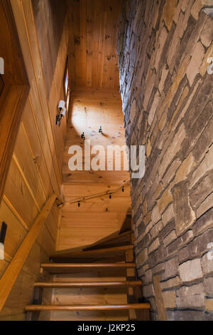 Escalier en bois flanquée de planche horizontale et de murs en pierre naturelle menant à l'étage étages à l'intérieur de style cottage et le bois profil journal télévision accueil. Banque D'Images