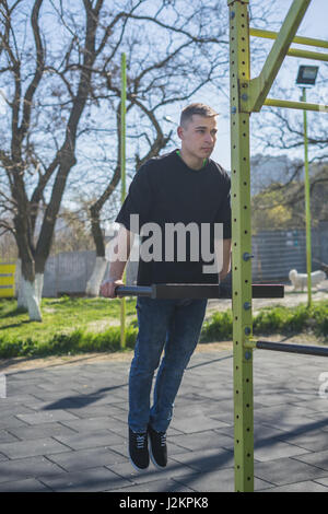 Jeune athlète faisant une part se tenir sur les barres parallèles dans une salle de sport en plein air Banque D'Images