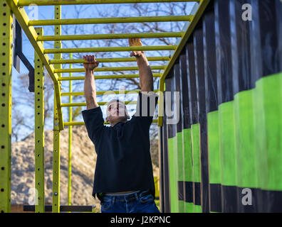 Athlète masculin swinging sur monkey bars Banque D'Images