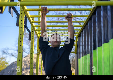 Athlète masculin swinging sur monkey bars Banque D'Images