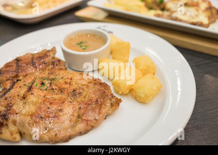 Escalope de porc avec sauce au poivre servi avec pommes de terre paillasson on white plate Banque D'Images