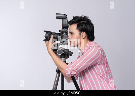 Young Asian photographer holding digital camera, tout en travaillant en studio Banque D'Images
