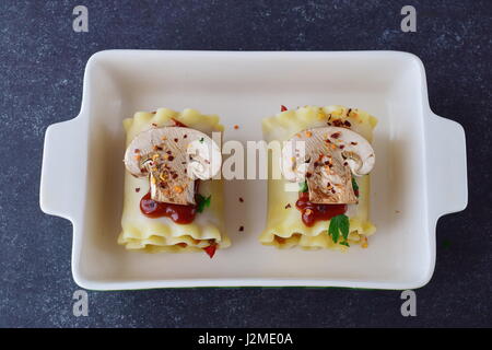 Lasagnes végétariennes en rouleaux avec des champignons, paprika, olives, sauce tomate dans une forme en céramique prêt pour un four. Alimentation saine. La nourriture végétarienne. Étape par étape de la cuisson. Banque D'Images