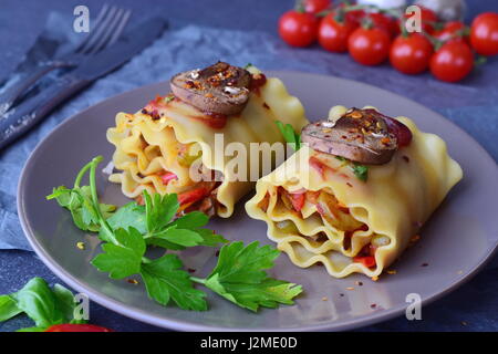 Prêt à manger lasagnes végétariennes en rouleaux avec des champignons, paprika, olives, sauce tomate sur une plaque en céramique marron. Alimentation saine. La nourriture végétarienne. Étape par étape de la cuisson. Banque D'Images