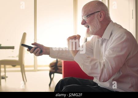 Vieil homme regardant la TV sur la table Banque D'Images