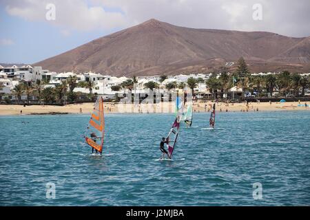 Les personnes qui apprennent à wind surf avec plage et le volcan en arrière-plan à Costa Teguise, Lanzarote, Îles Canaries Banque D'Images