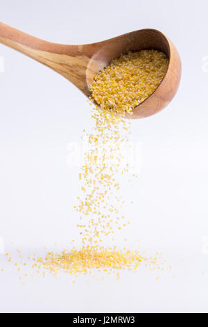 Les gruaux. Cuillère de gruau de blé tombant sur un fond blanc, isolé Banque D'Images