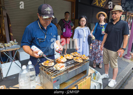 TOKYO, JAPON - 18 juillet 2016 - l'homme Jananese vendeur de rue pour ses fruits de mer cuisiniers clients en attente sur le marché aux poissons de Tsukiji à Tokyo, Japon, le 18 juillet 201 Banque D'Images