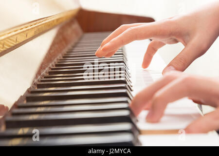 Close up of female hands à jouer du piano avec une main sur les touches, l'autre main flottant au-dessus et sur le point de frapper les touches, selective focus sur la main Banque D'Images