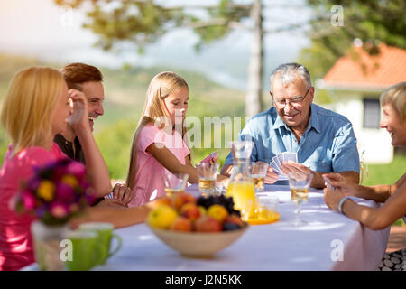 Family sitting at table des cartes à jouer dans la nature Banque D'Images