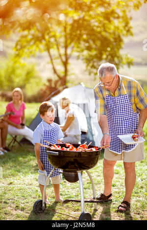 Grand-père et petit-fils de faire campagne sur un barbecue Banque D'Images