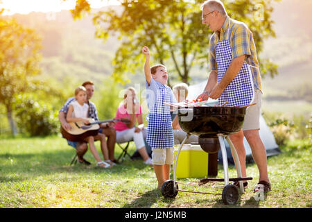 Heureux grand-père et petit-fils de faire un barbecue sur camping Banque D'Images