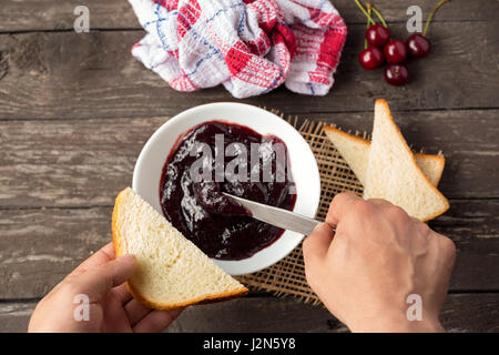 L'homme est préparer le petit-déjeuner et la propagation de la confiture sur la tranche de pain grillé Banque D'Images