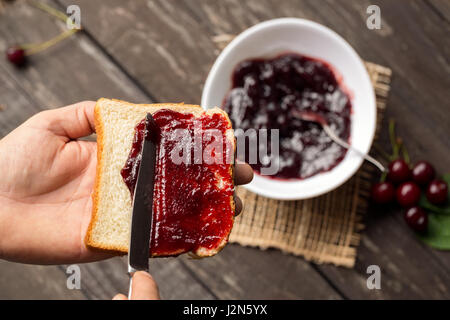 L'homme est préparer le petit-déjeuner et la propagation de la marmelade sur la tranche de pain grillé Banque D'Images