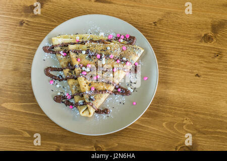 Vue de dessus avec crêpe délicieuse crème au chocolat et chocolat et pure servi sur assiette blanche sur une table en bois Banque D'Images