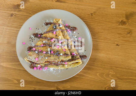 Vue de dessus avec crêpe délicieuse crème au chocolat et chocolat et pure servi sur assiette blanche sur une table en bois Banque D'Images