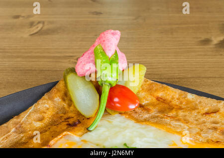 Gros plan du délicieux fromage cheddar avec crêpe servie sur une plaque gris sur une table en bois Banque D'Images