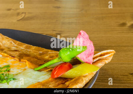 Gros plan du délicieux fromage cheddar avec crêpe servie sur une plaque gris sur une table en bois Banque D'Images