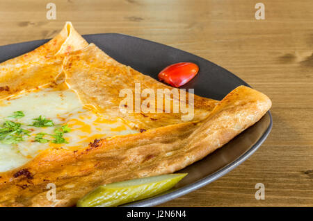Gros plan du délicieux fromage cheddar avec crêpe servie sur une plaque gris sur une table en bois Banque D'Images